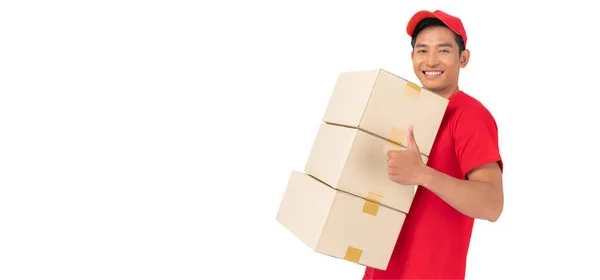 那个面带微笑的送货人身穿红帽子和空白T恤制服 站在一个白色背景的前面 手里拿着空白的纸板箱 — 图库照片