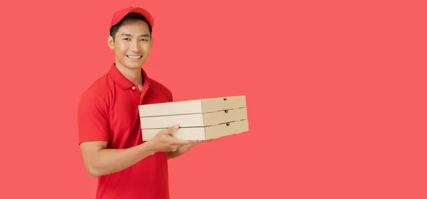 Usměvavý Poslíček Pizzy Stojí Červeném Pozadí Drží Krabici Pizzy Sobě — Stock fotografie