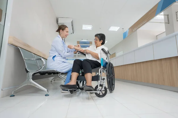 医生友好地坐在轮椅上询问和检查病人的健康状况 — 图库照片