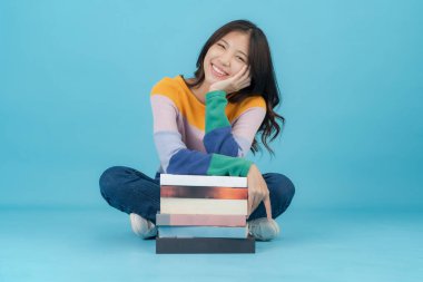 Mutlu bir şekilde gülümserken bir sürü kitabı olan güzel bir genç kadın.