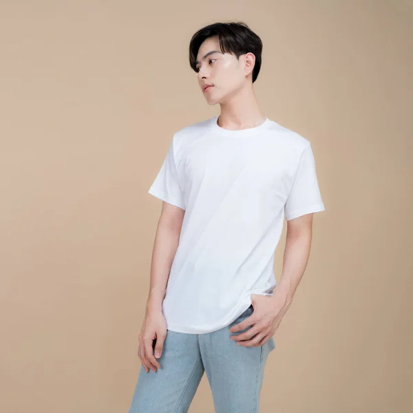 Mužský Módní Model Bílém Tričku Džínách Stojící Studiu Béžovém Pozadí — Stock fotografie