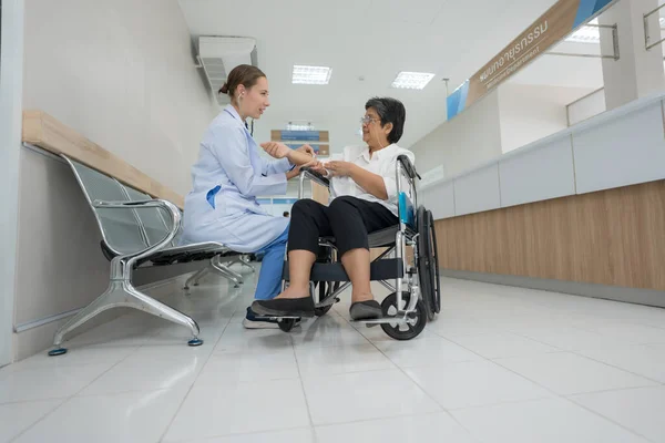 医生友好地坐在轮椅上询问和检查病人的健康状况 — 图库照片