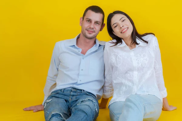 Couple Smiling Sitting Together Floor Looking Camera Yellow Background — Stock Photo, Image