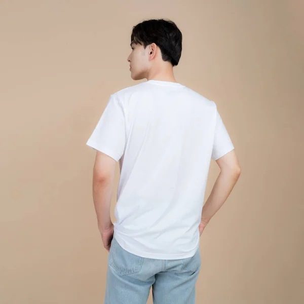 Mužský Módní Model Bílém Tričku Džínách Stojící Studiu Béžovém Pozadí — Stock fotografie