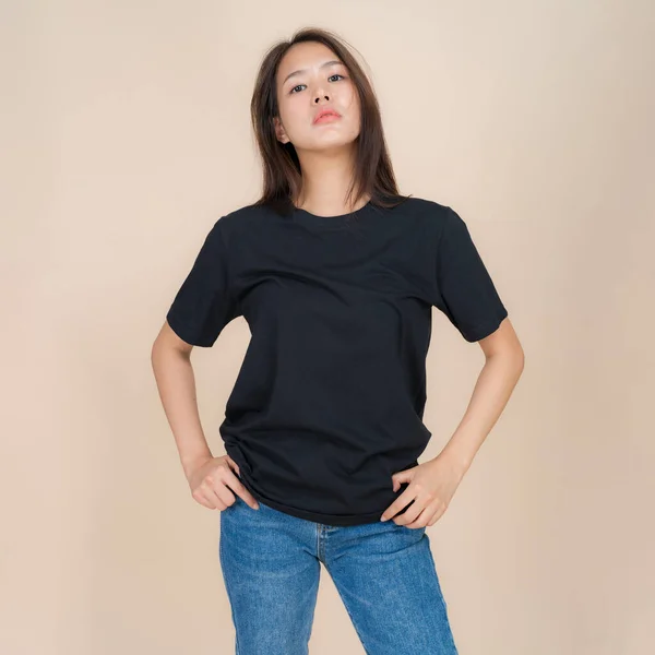 Modelka Kobieca Czarnej Koszulce Dżinsach Stojąca Studio Beżowym Tle Modny — Zdjęcie stockowe