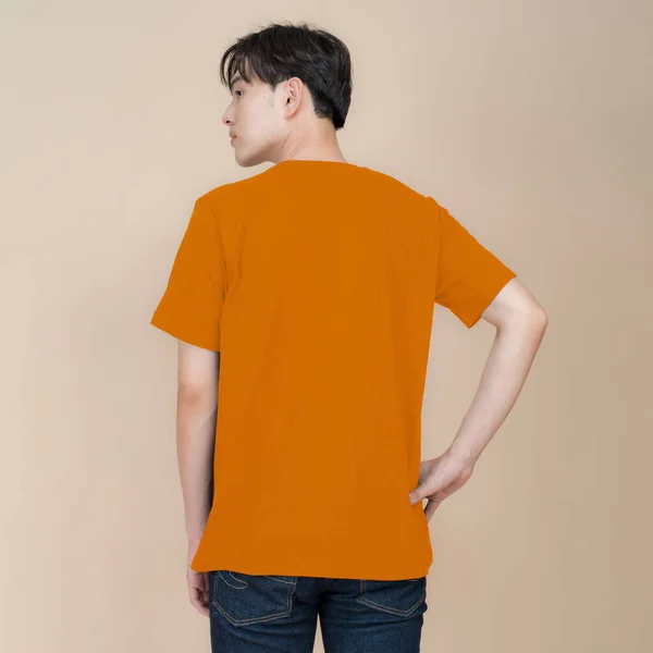 Male Fashion Model Orange Shirt Jeans Standing Studio Beige Background — Stock Photo, Image