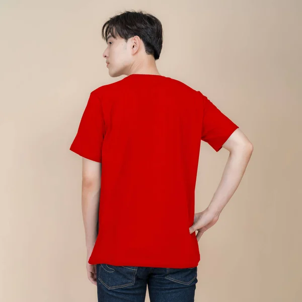 Mužský Módní Model Červeném Tričku Džínách Stojící Studiu Béžovém Pozadí — Stock fotografie