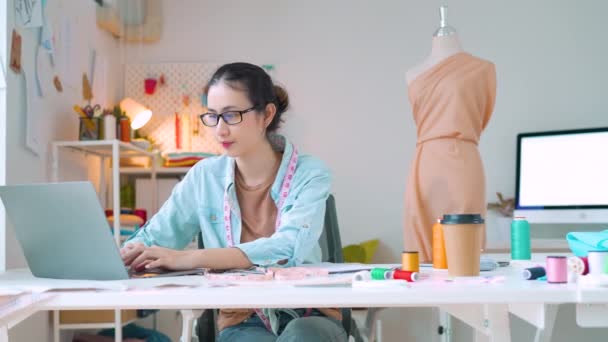 彼女のスタジオで幸せな女性起業家が彼女のデザインから新しい衣料品コレクションを作っています — ストック動画