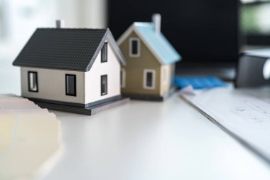 Dizüstü bilgisayar, hesap makinesi, planlar ve renk örnekleri yanında minyatür evler, emlak planlamasını sembolize ediyor