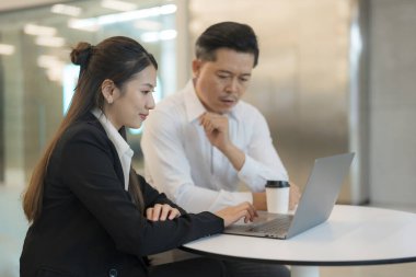 Modern bir ofis ortamında dizüstü bilgisayarla ciddi bir tartışmaya giren iki profesyonel.