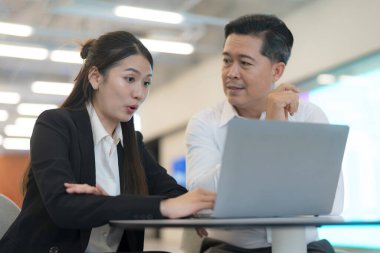 Modern bir ofis ortamında dizüstü bilgisayarla ciddi bir tartışmaya giren iki profesyonel.