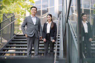 Kendine güvenen iş adamları ve iş kadını modern şehir ortamında merdivenlerden iniyorlar.