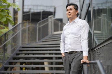 Resmi giyinmiş genç bir adam modern bir binanın merdivenlerinden aşağı iniyor.