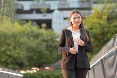 Gündüz vakti şehir merkezinde gülerken kendine güvenen ve motive olmuş görünen şık ve modern iş kadını.