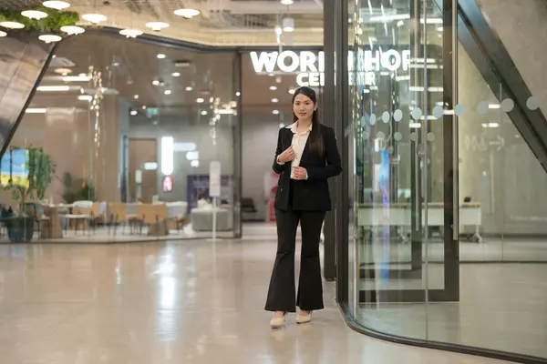 Professional woman in suit smiling outside a modern corporate building