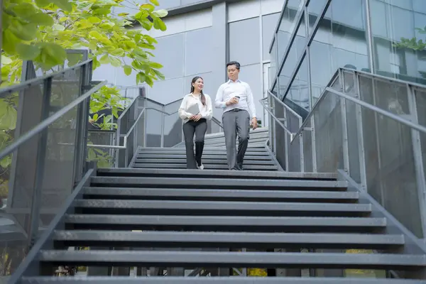 Two professionals in conversation while descending outdoor stairs