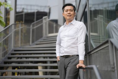 Resmi giyinmiş genç bir adam modern bir binanın merdivenlerinden aşağı iniyor.