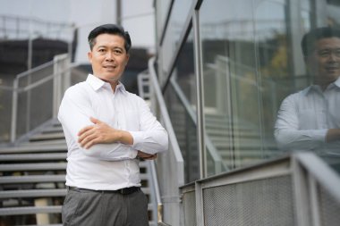 Resmi giyinmiş genç bir adam modern bir binanın merdivenlerinden aşağı iniyor.