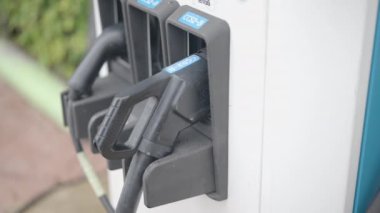 Şarj istasyonunda bir elektrikli araba şarj aletinin fişini çekmek. Şarj portu ile etkileşimi gösterir, fişi çeker ve arabanın şarj kapağını kapatır