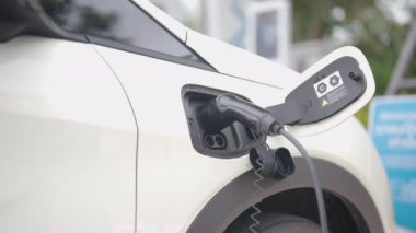 Şarj istasyonunda bir elektrikli araba şarj aletinin fişini çekmek. Şarj portu ile etkileşimi gösterir, fişi çeker ve arabanın şarj kapağını kapatır