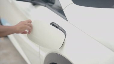Şarj istasyonunda bir elektrikli araba şarj aletinin fişini çekmek. Şarj portu ile etkileşimi gösterir, fişi çeker ve arabanın şarj kapağını kapatır