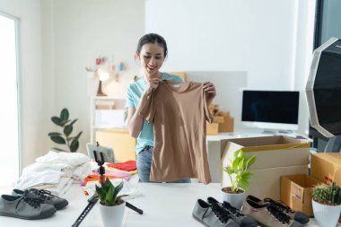 Asyalı bir kadın, bir iş sahibi, akıllı telefonuyla online yayın için bir video kaydediyor, açılışını sergiliyor. Gülümsüyor, müşterilerle iletişim kurmak için teknolojiyi kucaklıyor.