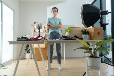 Asyalı bir kadın, bir iş sahibi, akıllı telefonuyla online yayın için bir video kaydediyor, açılışını sergiliyor. Gülümsüyor, müşterilerle iletişim kurmak için teknolojiyi kucaklıyor.