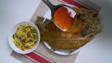 Şef, kızarmış balığın üzerine lezzetli bir sos döker, canlı bir mango salatasıyla birlikte servis edilir, ve nefis bir aşçılık deneyimi yaratır.