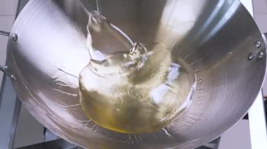Sarı başlıklı plastik bir şişeden gaz sobasındaki paslanmaz çelikten tavaya akan sebze yağı, mutfakta lezzetli bir yemek hazırlığı için sahneyi hazırlıyor.
