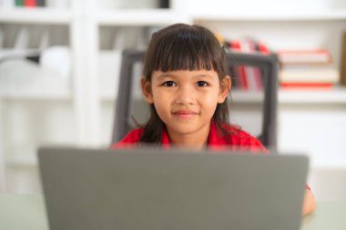 Odaklanmış Asyalı genç kız dizüstü bilgisayar kullanıyor, evde online çalışıyor, uzaktan öğrenme ve çevrimiçi eğitimin tadını çıkarıyor, e-öğrenim faaliyetleri ve evde eğitim görüyor.