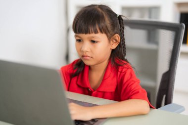 Odaklanmış Asyalı genç kız dizüstü bilgisayar kullanıyor, evde online çalışıyor, uzaktan öğrenme ve çevrimiçi eğitimin tadını çıkarıyor, e-öğrenim faaliyetleri ve evde eğitim görüyor.