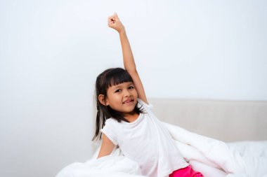 Mutlu çocuk sabah rahat bir yatakta uyandıktan sonra esniyor, yeni bir günün tadını çıkarıyor, pozitif duygulara sahip oluyor ve rahatlıyor.