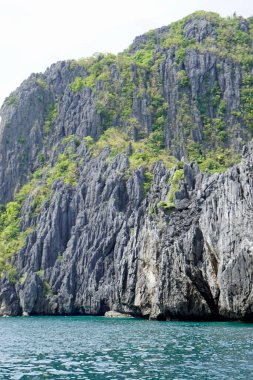 El Nido Takımadası 'ndaki mavi denizde devasa kireçtaşı kayaları.
