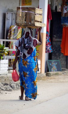 Paj, Zanzibar - Ekim 2024: Kafasında mal taşıyan geleneksel giyinmiş kadın