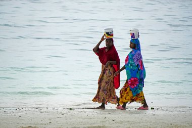 Paje, Zanzibar - Ekim 2024: Kafasında mal taşıyan geleneksel giyinmiş kadınlar