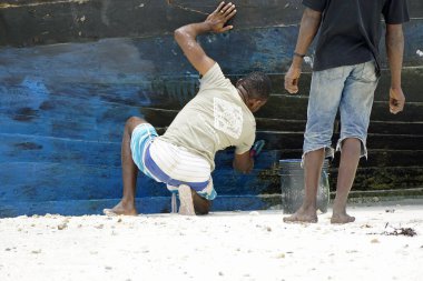 Nungwi, Zanzibar - Ekim 2024: Yerel balıkçı eski ahşap teknesini boyadı