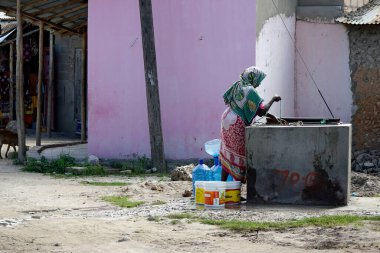 Nungwi, Zanzibar - october 2024: Woman pumping for Drinking water from the water whole clipart