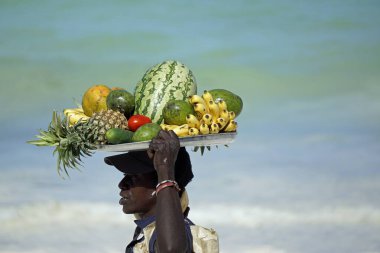 Paje, Zanzibar - Ekim 2024: Kafasında taze meyve taşıyan yerel satıcı