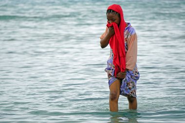 Nungwi, Zanzibar - Ekim 2024: Sular çekildiğinde okyanustan deniz ürünleri toplayan kadın