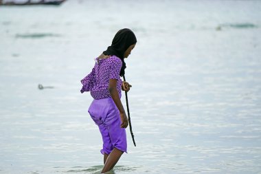 Nungwi, Zanzibar - Ekim 2024: Sular çekildiğinde okyanustan deniz ürünleri toplayan kadın