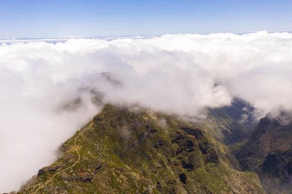 Drone view of mountain trail path submerged in fog during summer day