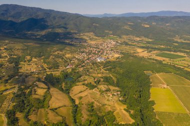 Drone photography of small rural town surrounded by agricultural fields, vineyards and olive trees during summer day
