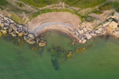drone photography of rocky cliff and small beach during summer evening