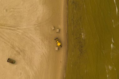 Drone photography of beach and excavator working in it during summer cloudy day