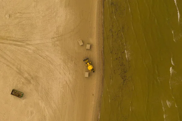 Drone photography of beach and excavator working in it during summer cloudy day