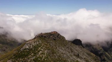 Dağın zirvesine giden dağ yürüyüşünün ve güneşli yaz günlerinde bulutlu manzaranın insansız hava aracı görüntüleri.