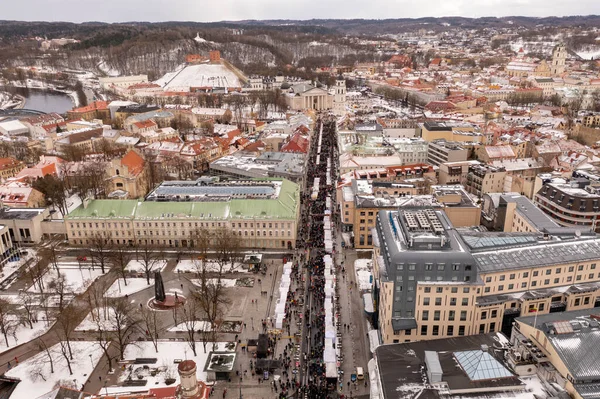 Drone photography of fair in a city center and a large crowd of people during winter cloudy day.