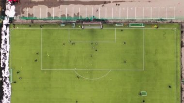 Kışın bulutlu bir günde futbol sahasında futbol antrenmanının drone görüntüleri. Tam üstte.