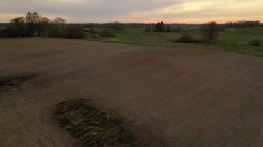 Zirai tarlaların insansız hava aracı görüntüleri ve bahar akşamında traktör süren bir çiftçi. Yüksek açı görünümü
