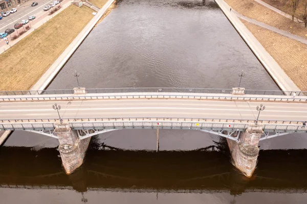 Bahar bulutlu bir günde şehir manzarasında bir nehrin üzerindeki köprünün insansız hava aracı fotoğrafçılığı. Yüksek açı görünümü.